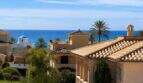 Außenansicht einer mediterranen Villa in Portixol mit Terrakotta-Dächern, Palmen und Meerblick auf Mallorca.