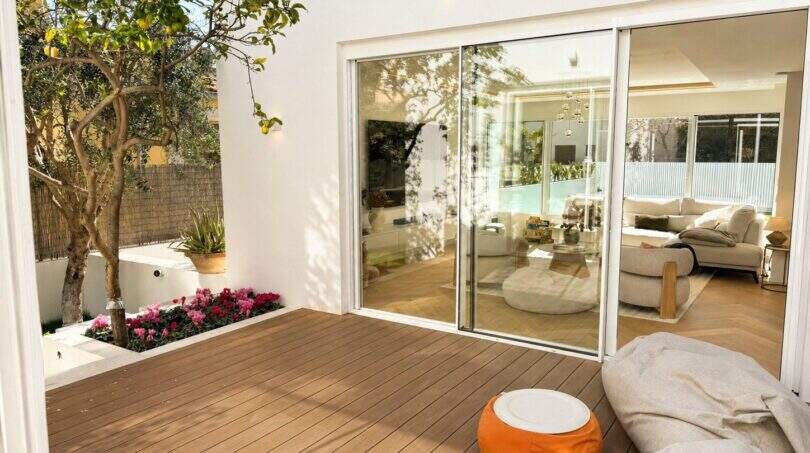 Sonnige Terrasse mit Holzboden und Glasschiebetüren zum eleganten Wohnzimmer der Designvilla in Portixol
