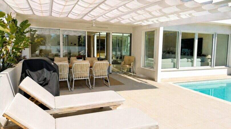 Sonnige Poolterrasse der Designvilla in Portixol mit Loungebetten, Pergola und elegantem Außenbereich.