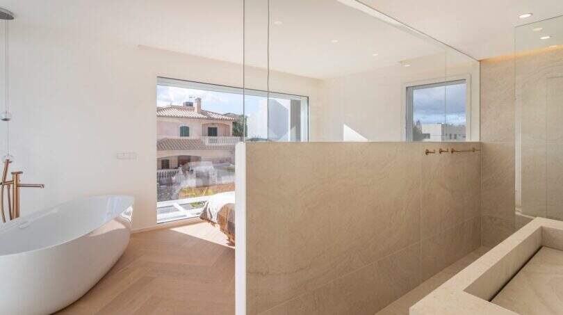 Helles Luxusbad der Designvilla in Portixol mit freistehender Badewanne, Natursteindusche und Roségold-Armaturen.