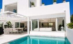 Außenansicht der Designvilla in Portixol mit türkisem Pool, weißer Fassade und offenem Wohnbereich