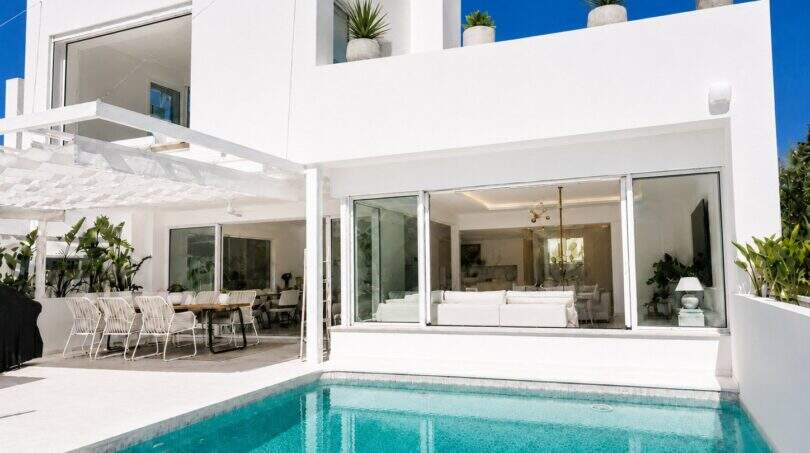Außenansicht der Designvilla in Portixol mit türkisem Pool, weißer Fassade und offenem Wohnbereich