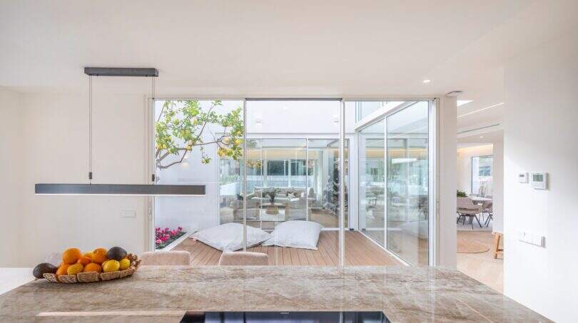 Moderne Küche der Designvilla in Portixol mit Marmorinsel und Blick auf den lichtdurchfluteten Innenpatio
