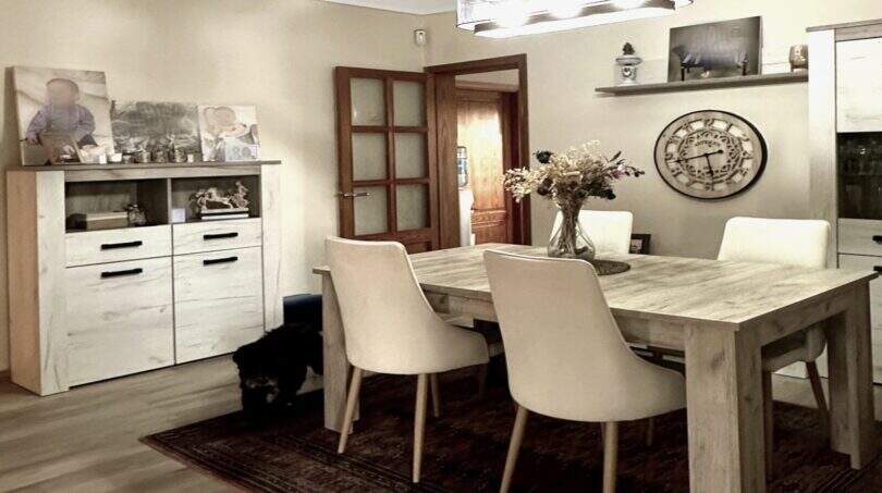 Helles Esszimmer der Mallorca-Finca mit Holztisch, weißen Stühlen, Sideboard und elegantem Kronleuchter.