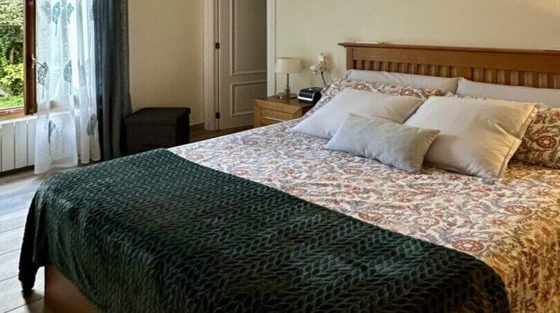 Helles Schlafzimmer der Mallorca-Finca mit Doppelbett, Holzboden, Klimaanlage und Gartenblick