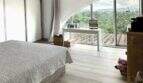 Helles Schlafzimmer der Finca Marratxí mit Bogenfenster, Parkettboden und Blick auf grüne Landschaft.