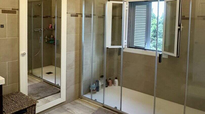 Geräumiges Badezimmer der Mallorca-Finca mit zwei Duschabteilen, Fenster und Holzoptikboden in Marratxí