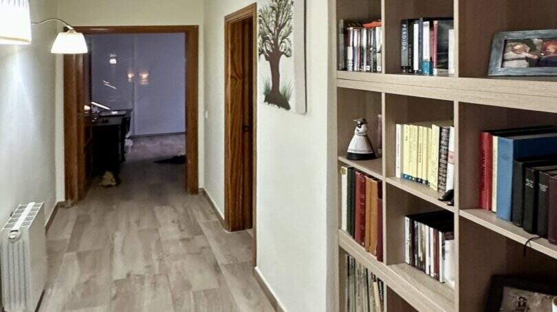 Heller Flur der Mallorca-Finca mit großem Bücherregal, Holzboden und Durchblick zu weiteren Zimmern