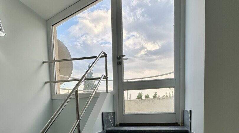 Treppenhaus der Finca Marratxí mit schwarzem Marmortreppe, Edelstahlgeländer und großer Glasfront mit Himmelsblick