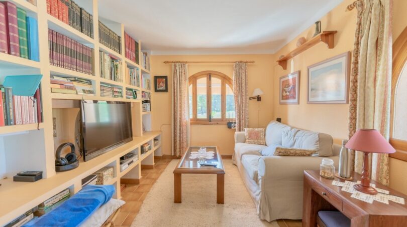 Wohnzimmer mit maßgefertigten Einbauregalen und eleganter Bogenöffnung zum Terrassenbereich
