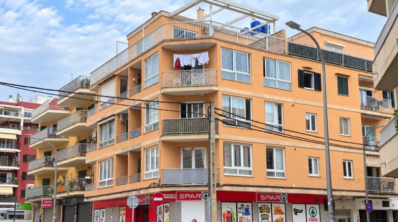 Außenansicht eines orangefarbenen Wohngebäudes in Playa de Palma mit Balkonen und SPAR-Geschäft im Erdgeschoss.