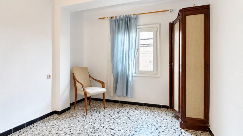 Helles Schlafzimmer mit Terrazzoboden, blauem Vorhang, Holzstuhl und antikem Kleiderschrank nahe Playa de Palma