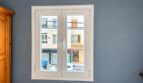 Weißes Doppelflügelfenster in grauem Zimmer mit Blick auf Stadtstraße in Playa de Palma, Mallorca