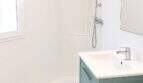 Modernes Badezimmer mit Eckdusche, petrolblauem Waschtischunterschrank und weißen Wänden in Palma-Stadtwohnung