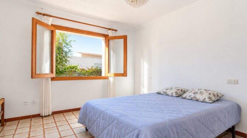 Helles Schlafzimmer mit Panoramafenster und Ausblick ins Grüne