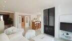 Helles Wohnzimmer mit weißen Sofas, modernem Kaminofen und offener Küche in Villa bei Cala Mandia