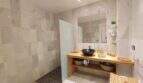 Modernes Badezimmer mit begehbarer Dusche, Holzwaschtisch und schwarzem Aufsatzbecken in der Villa Cala Mandia