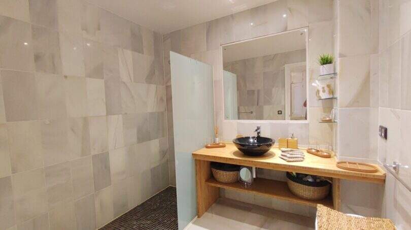 Modernes Badezimmer mit begehbarer Dusche, Holzwaschtisch und schwarzem Aufsatzbecken in der Villa Cala Mandia