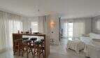 Helles Wohnzimmer mit Holz-Bartheke, flauschigen Barhockern und weißen Sofas in Villa über Cala Mandia