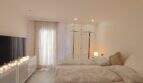 Helles Schlafzimmer mit Doppelbetten, weißem Einbauschrank, TV und dekorativer Lichterkette in Cala Mandia