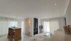 Helles Wohnzimmer mit Kamin, offener Küche, weißen Möbeln und großen Fenstern in Villa bei Cala Mandia