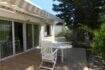 Sonnige Terrasse mit weißen Gartenmöbeln, Markise und Glasschiebetür beim Chalet in Portocolom