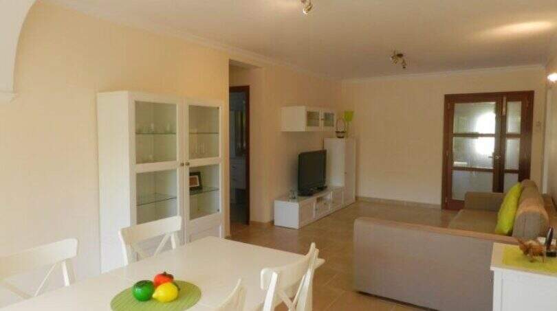 Helles Wohnzimmer mit weißem Esstisch, Vitrinenschrank und Sofa im modernen Chalet in Portocolom