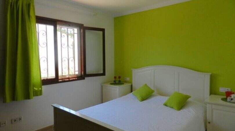 Helles Schlafzimmer im Chalet Portocolom mit Doppelbett, grüner Akzentwand und weißen Möbeln, Hafennähe 100 m.