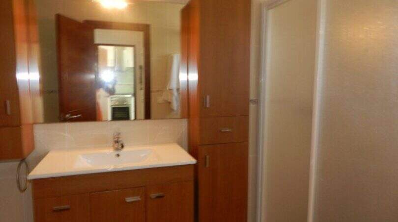 Modernes Badezimmer mit Holzunterschrank, Waschbecken, Duschkabine und Hochschrank im Chalet Portocolom